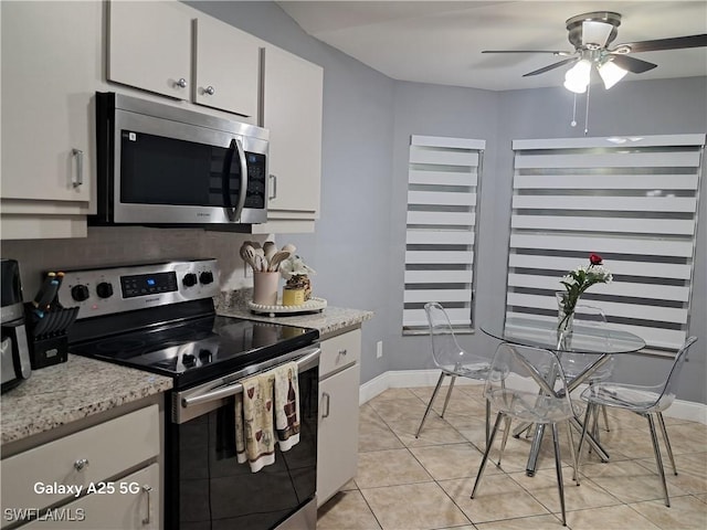 kitchen with light tile patterned floors, ceiling fan, stainless steel appliances, white cabinets, and light stone countertops