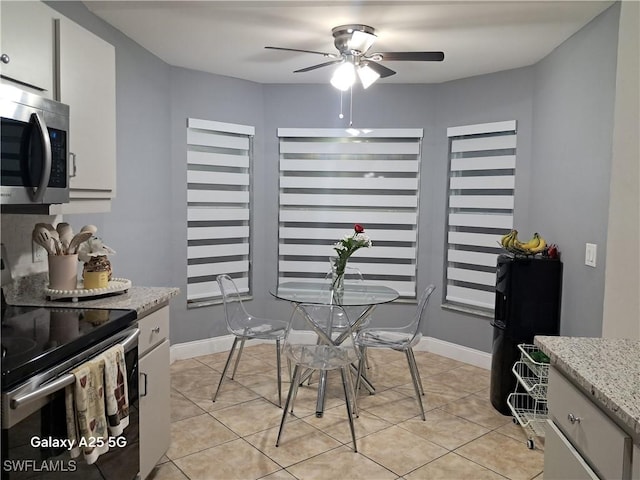 dining area with ceiling fan, baseboards, and light tile patterned floors