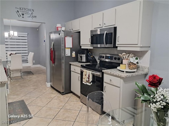 kitchen with light tile patterned floors, appliances with stainless steel finishes, white cabinets, and decorative light fixtures