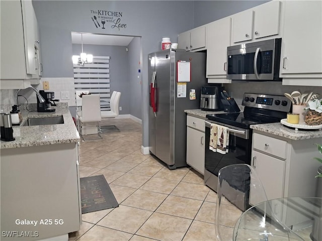 kitchen featuring light tile patterned floors, sink, white cabinetry, decorative light fixtures, and stainless steel appliances