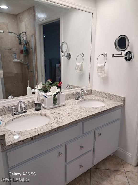 bathroom with a shower with shower door, vanity, and tile patterned flooring