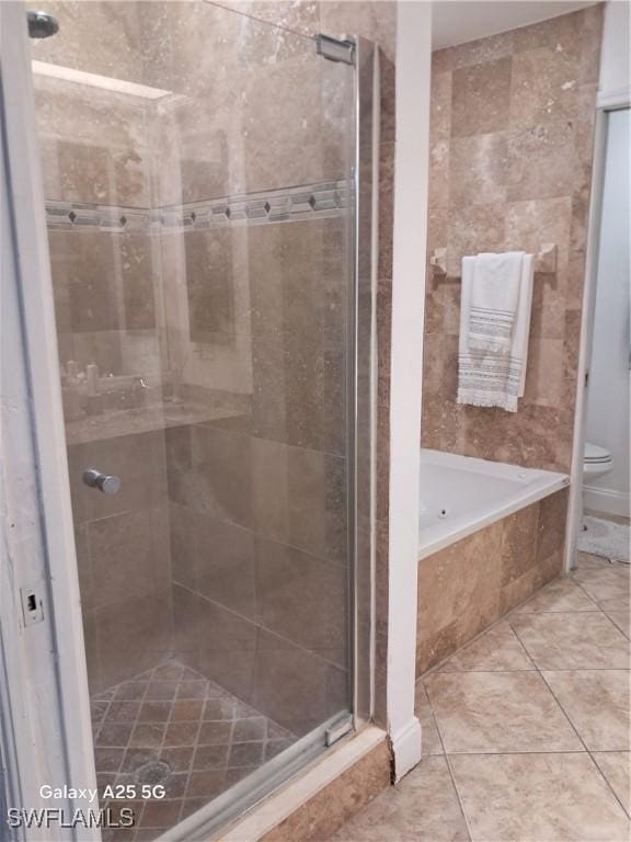 full bathroom featuring toilet, tile patterned flooring, a relaxing tiled tub, and a stall shower