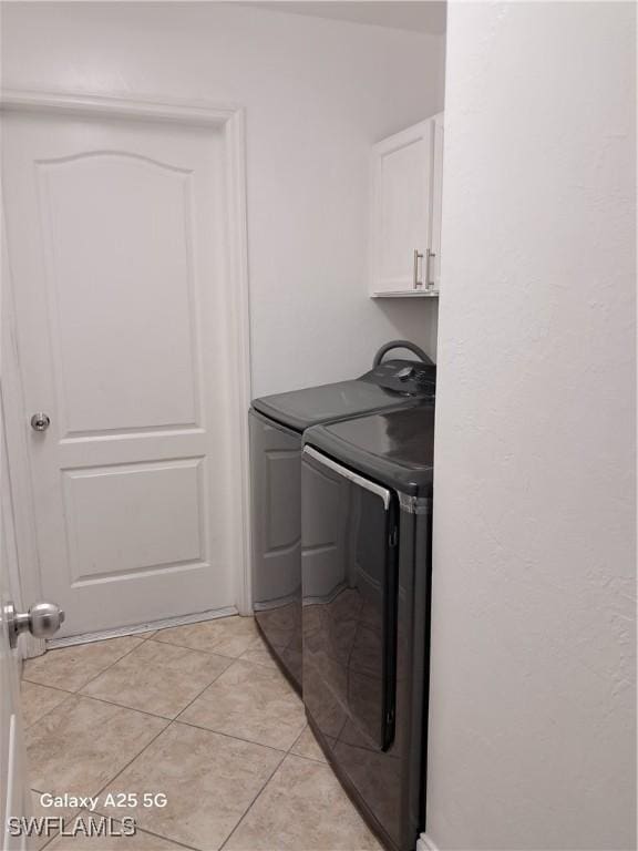 washroom featuring cabinet space, independent washer and dryer, and light tile patterned floors