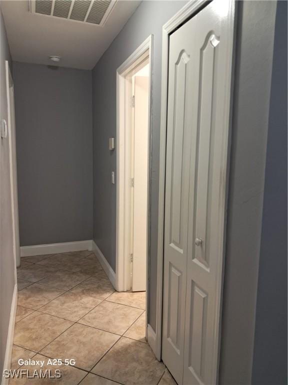 hallway featuring baseboards, visible vents, and light tile patterned floors