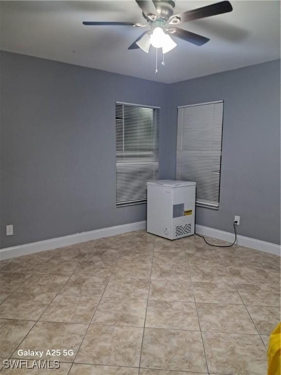 unfurnished room featuring baseboards, ceiling fan, and light tile patterned floors