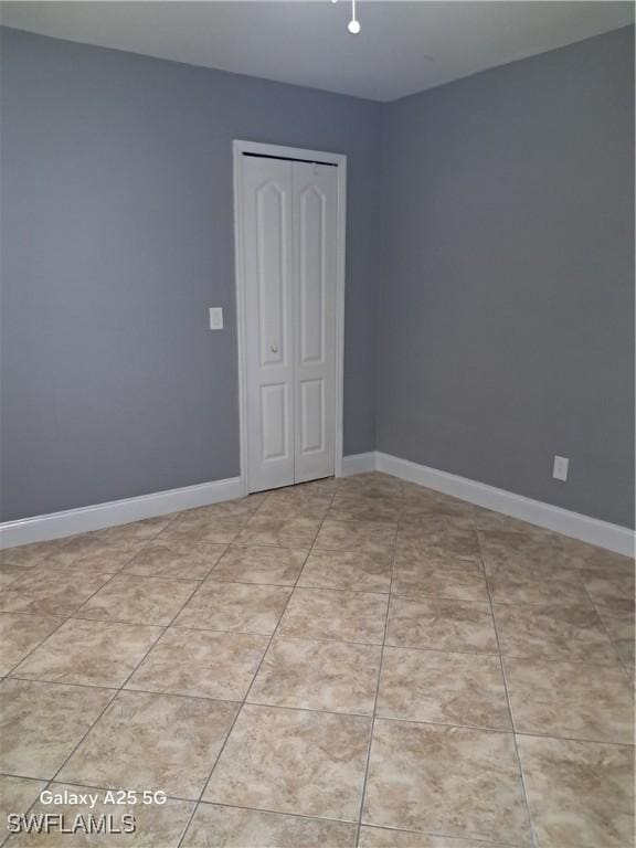 spare room featuring baseboards and light tile patterned flooring