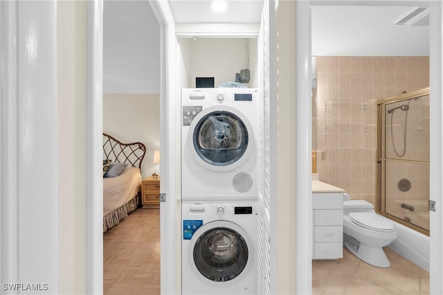 laundry room with laundry area, stacked washing maching and dryer, and light tile patterned floors