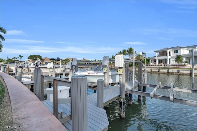 dock area with a water view, boat lift, and a residential view