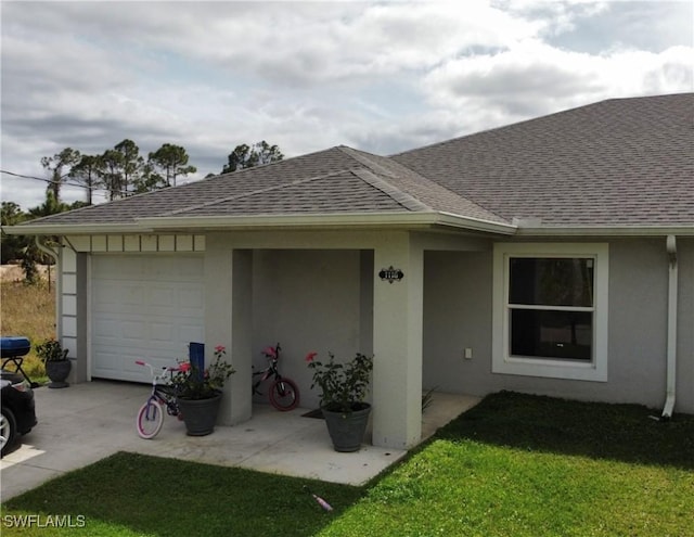 exterior space featuring a garage, a shingled roof, concrete driveway, and a front yard