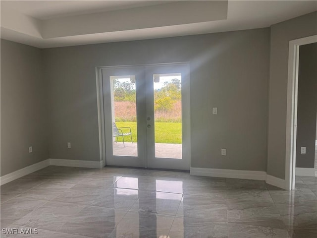 spare room with marble finish floor, baseboards, a raised ceiling, and french doors