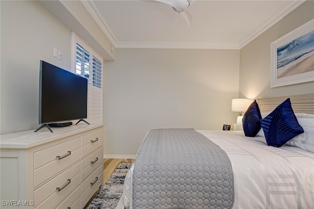 bedroom featuring baseboards, crown molding, and light wood finished floors