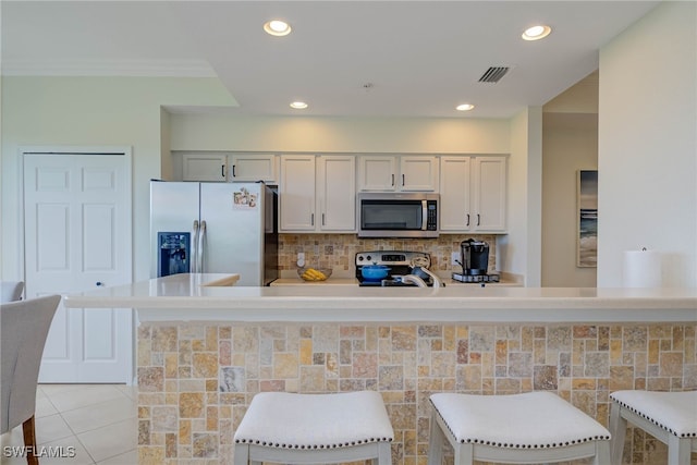 kitchen with light tile patterned floors, a breakfast bar area, stainless steel appliances, and light countertops