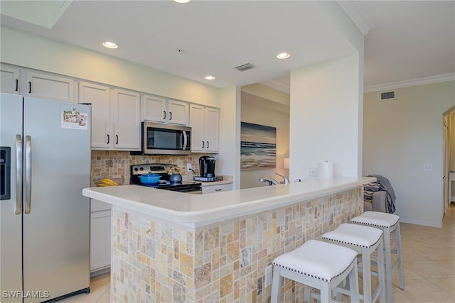 kitchen featuring a breakfast bar area, light tile patterned floors, stainless steel appliances, light countertops, and visible vents