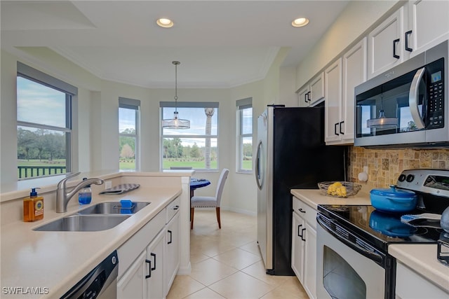 kitchen with decorative light fixtures, stainless steel appliances, light countertops, white cabinetry, and a sink