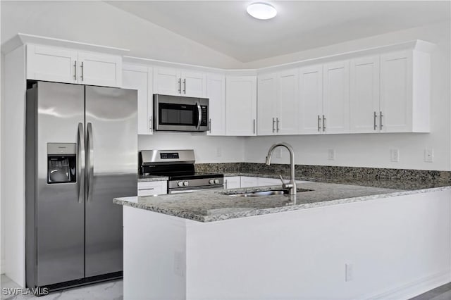 kitchen with a peninsula, white cabinets, stainless steel appliances, and a sink