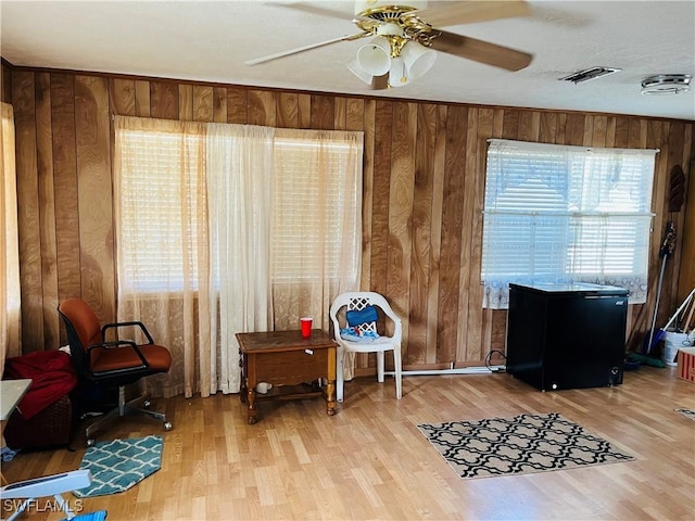 interior space featuring hardwood / wood-style flooring, ceiling fan, and wood walls