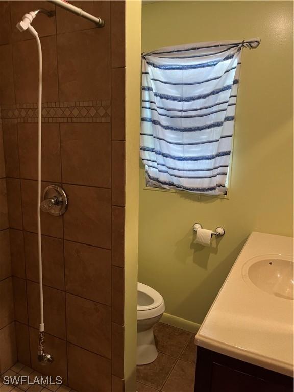 bathroom with tile patterned floors, toilet, vanity, and a tile shower