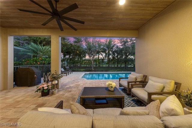 pool at dusk with a fenced backyard, a grill, a ceiling fan, a patio, and an outdoor living space