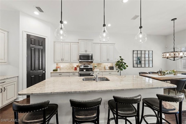 kitchen featuring tasteful backsplash, visible vents, appliances with stainless steel finishes, light stone counters, and a sink