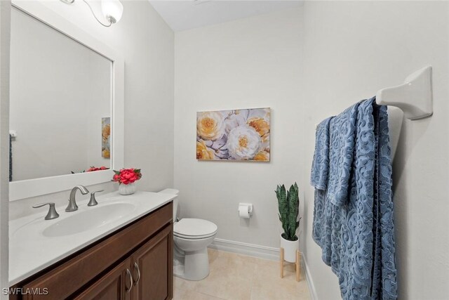 bathroom with toilet, vanity, tile patterned floors, and baseboards