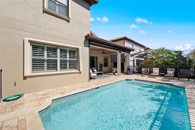 view of swimming pool featuring area for grilling, fence, a ceiling fan, a fenced in pool, and a patio area