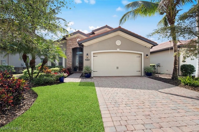 mediterranean / spanish-style house with stone siding, a garage, a front yard, stucco siding, and decorative driveway