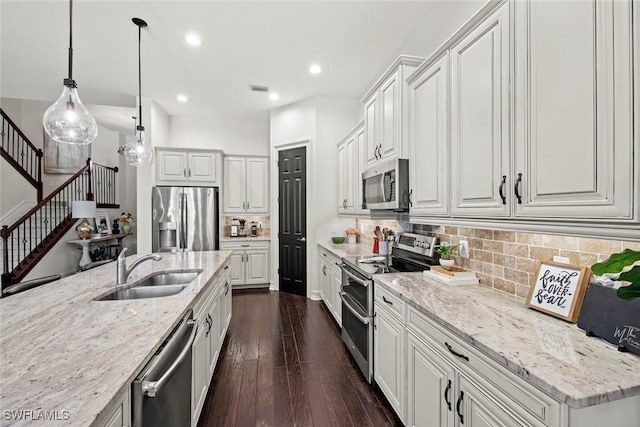 kitchen featuring dark wood finished floors, decorative backsplash, appliances with stainless steel finishes, white cabinetry, and a sink