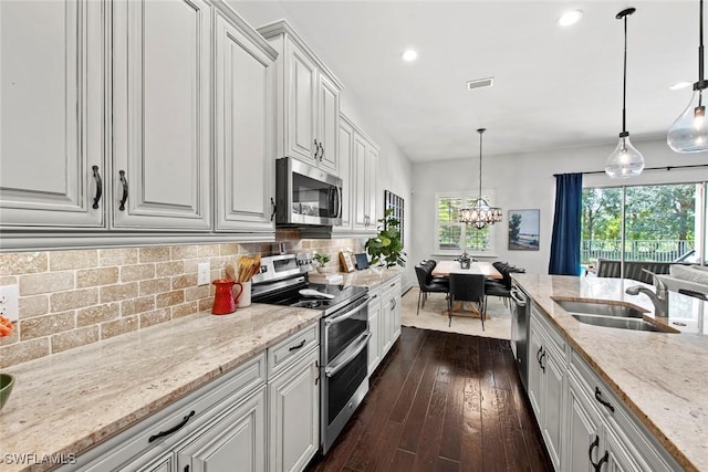 kitchen featuring white cabinets, light stone counters, stainless steel appliances, visible vents, and a sink