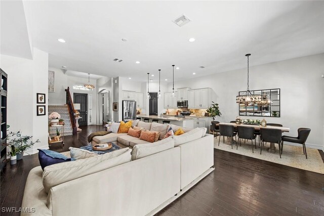 living room with an inviting chandelier, dark wood-style floors, visible vents, and recessed lighting