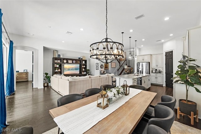 dining area with visible vents, dark wood finished floors, stairs, a notable chandelier, and recessed lighting