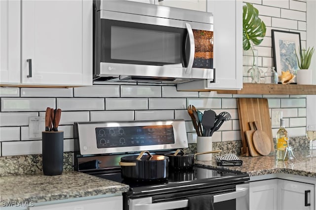 kitchen with tasteful backsplash, appliances with stainless steel finishes, white cabinetry, and light stone countertops