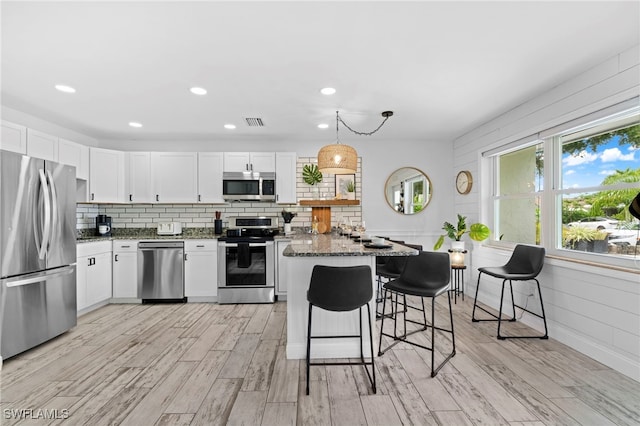 kitchen featuring hanging light fixtures, white cabinetry, appliances with stainless steel finishes, and dark stone countertops