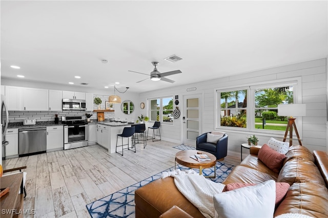 living room with light wood-style flooring, recessed lighting, visible vents, and a ceiling fan