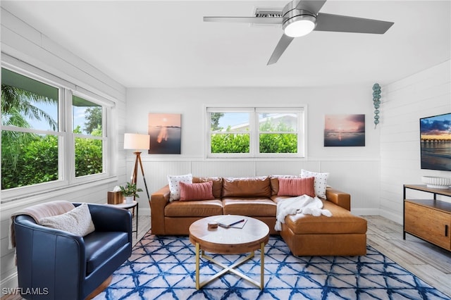 living room with a ceiling fan, a wainscoted wall, a healthy amount of sunlight, and wood finished floors