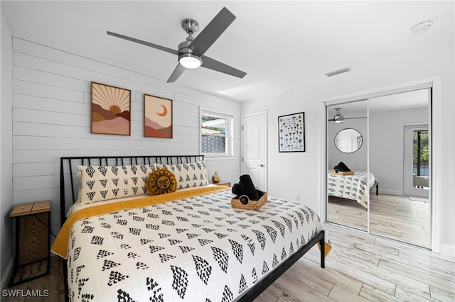 bedroom with light wood finished floors, multiple closets, visible vents, ceiling fan, and baseboards