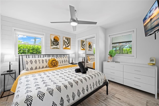 bedroom with multiple windows, light wood-type flooring, a closet, and a ceiling fan