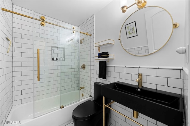 bathroom featuring toilet, enclosed tub / shower combo, and tile walls