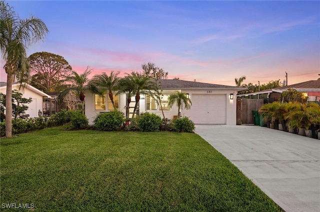 view of front facade with driveway, a garage, a front yard, and stucco siding