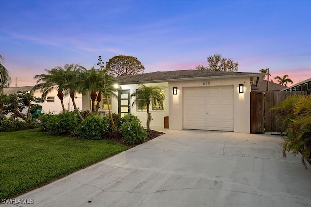 single story home with driveway, a lawn, an attached garage, and stucco siding