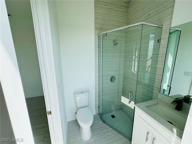 bathroom with toilet, vanity, and a shower with shower door