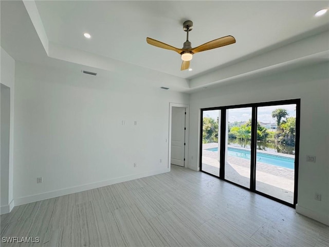 spare room featuring a tray ceiling and ceiling fan