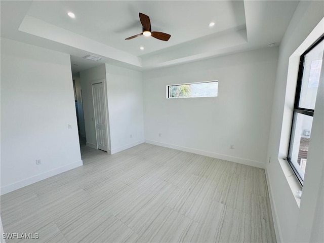 empty room featuring a tray ceiling and ceiling fan