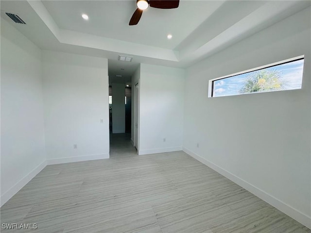 spare room featuring ceiling fan and a raised ceiling