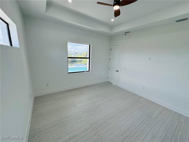 spare room featuring ceiling fan and a raised ceiling