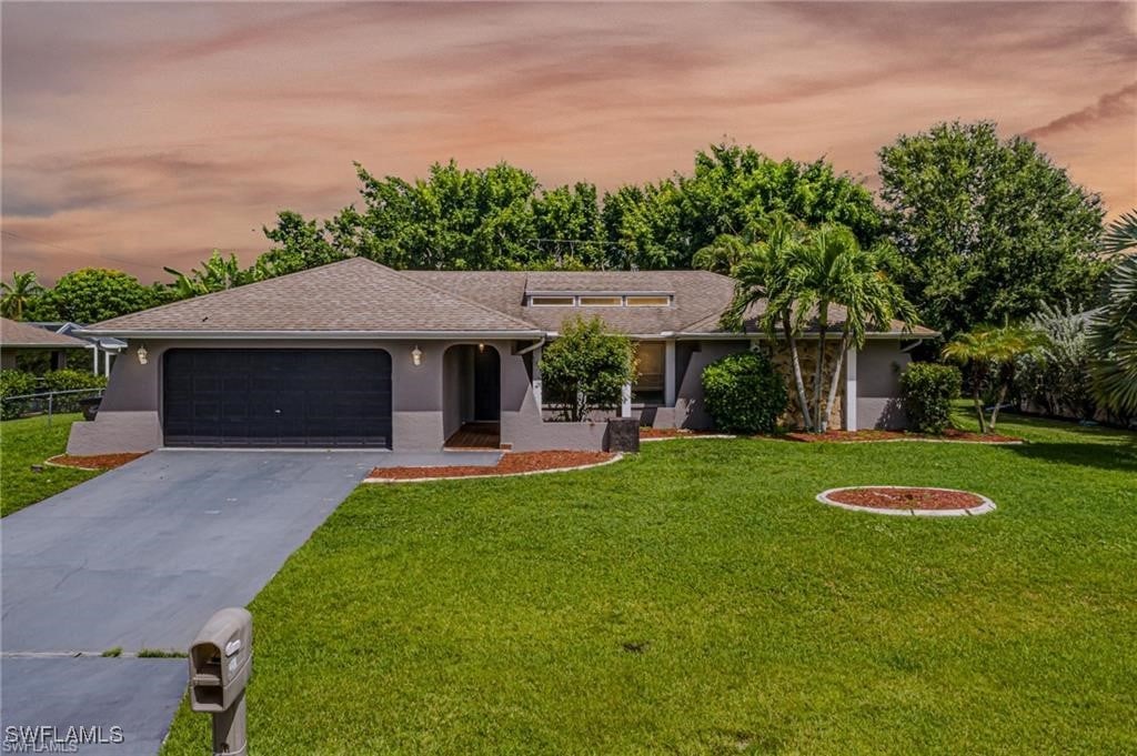 single story home with a garage and a yard