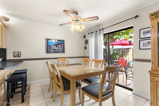 dining room featuring light tile patterned floors, ornamental molding, ceiling fan, a textured ceiling, and baseboards