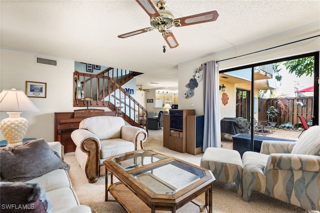 living area featuring stairs, a textured ceiling, visible vents, and light colored carpet