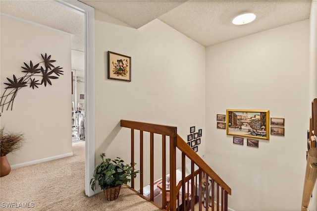 stairs with a textured ceiling, carpet flooring, and baseboards