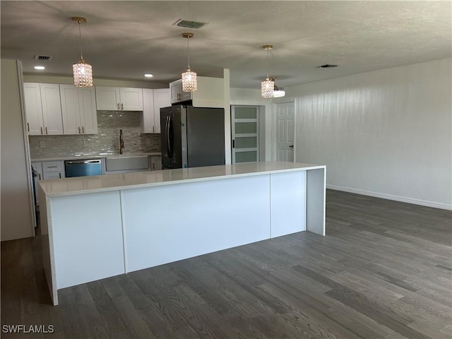 kitchen featuring dishwashing machine, white cabinets, decorative light fixtures, sink, and black fridge