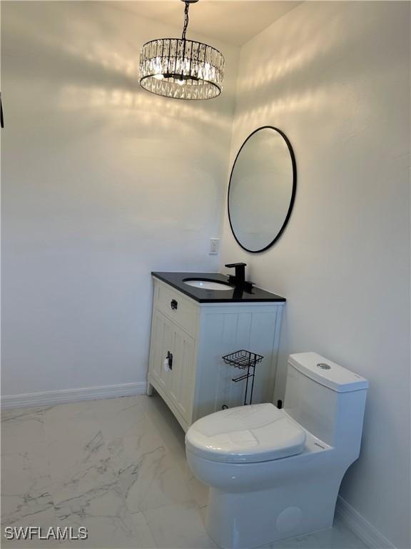 bathroom with toilet, a chandelier, and vanity